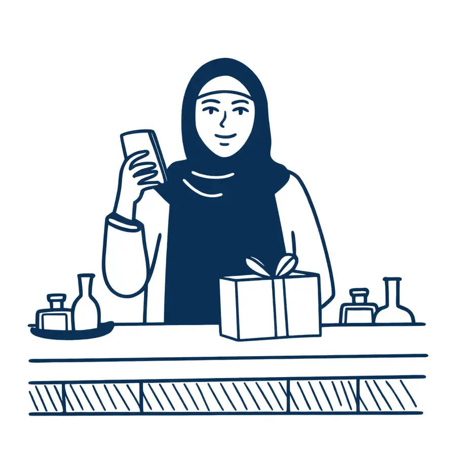 A woman in an abaya at her perfume shop counter, reading a message and opening a gift box
